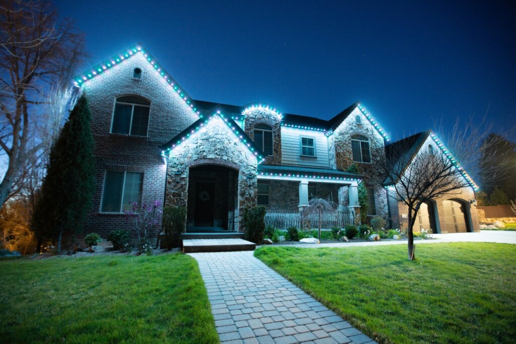 Home with cool white permanent roofline lights and lit front walkway