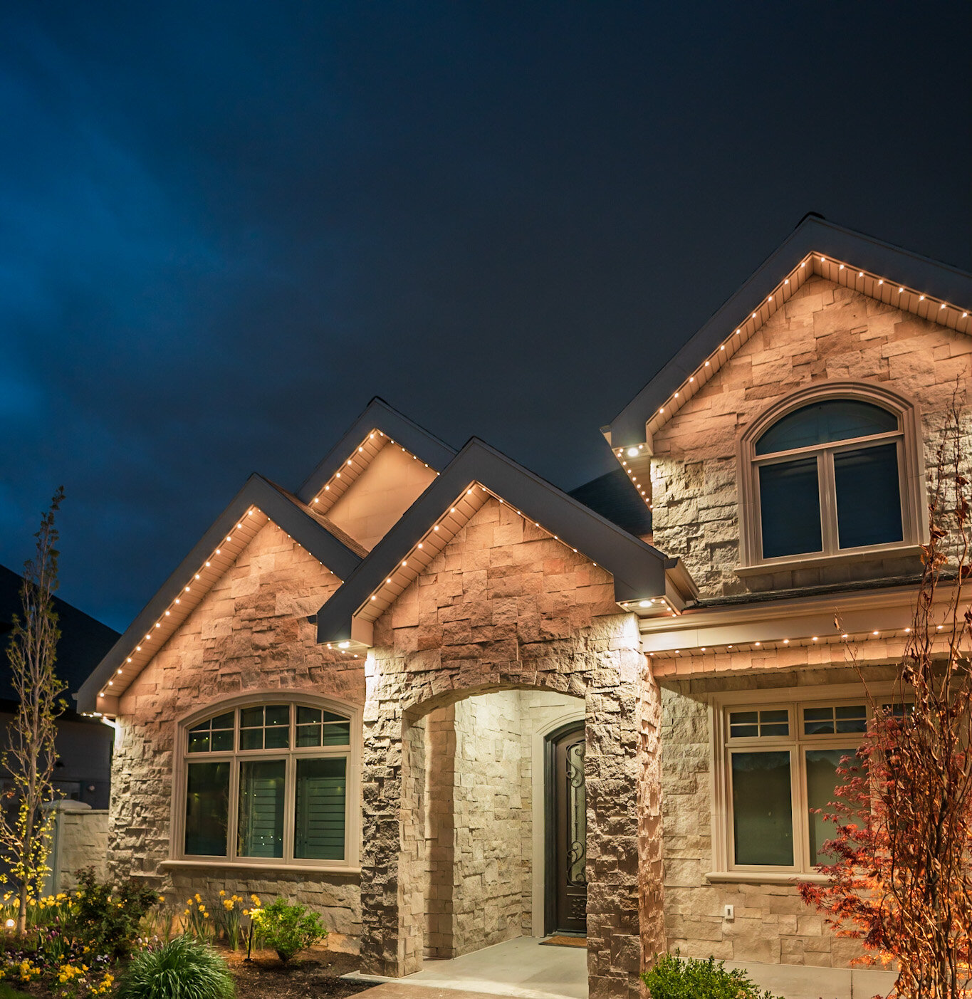 Accent warm white stone home with permanent outdoor lighting