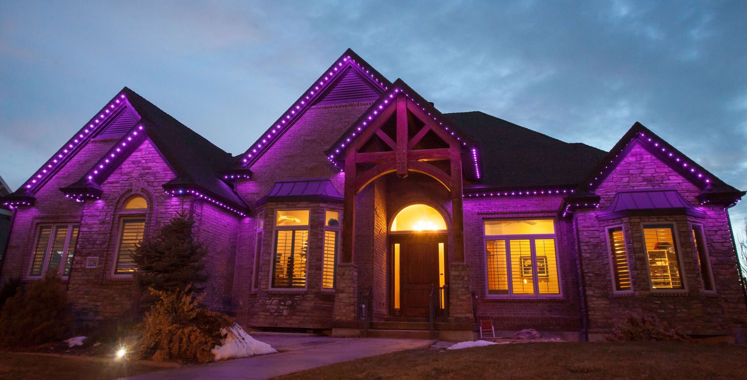 Home with purple permanent roofline lighting at dusk for game day