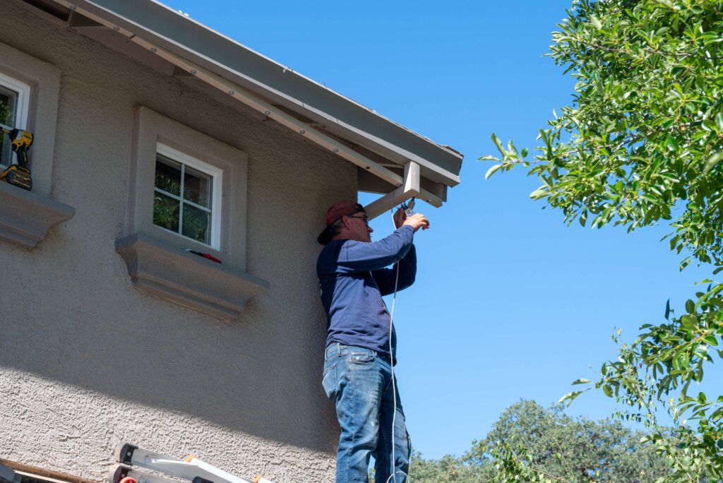 Happy Lites technician installing permanent lights along a home roofline