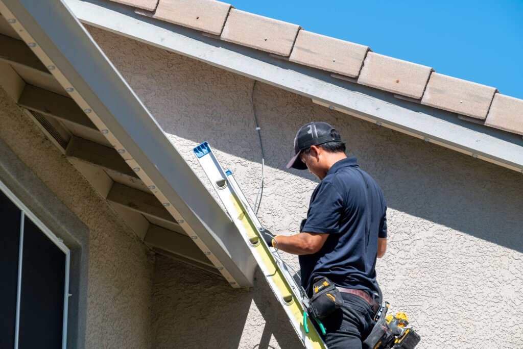 Happy Lites technician on a ladder at an eave installing permanent lights