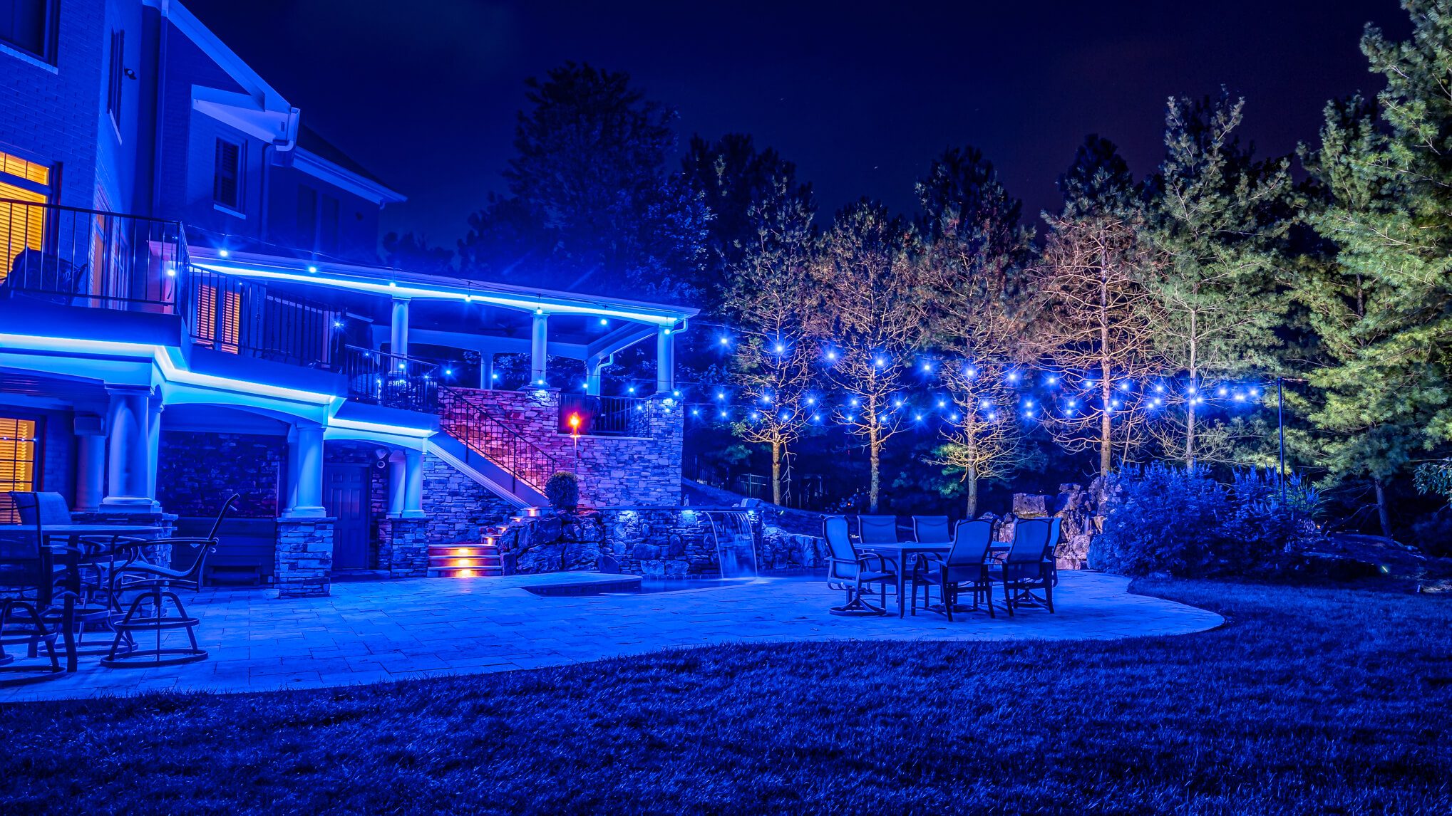 Backyard pool, patio and trees with blue pool permanent outdoor lighting