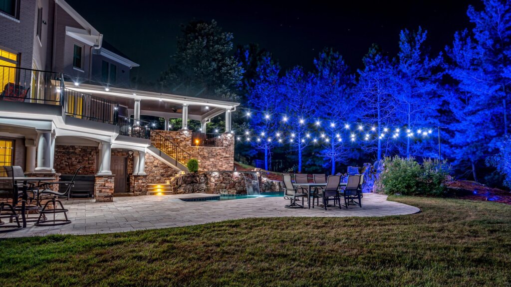 Backyard pool, patio and trees with blue trees permanent outdoor lighting