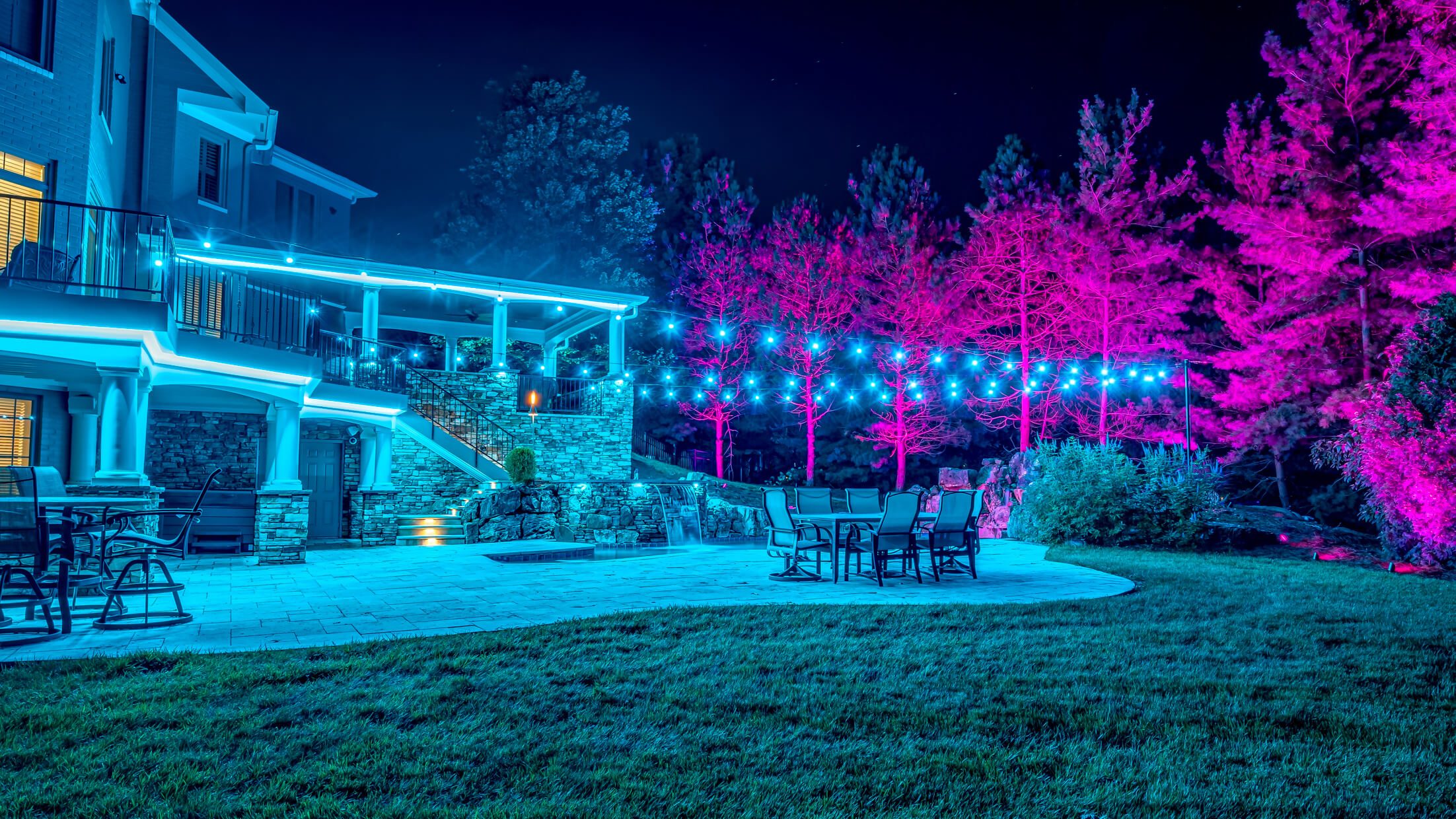 Backyard pool, patio and trees with cyan and pink permanent outdoor lighting