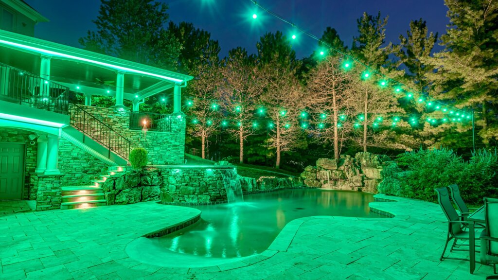 Backyard pool, patio and trees with green pool permanent outdoor lighting