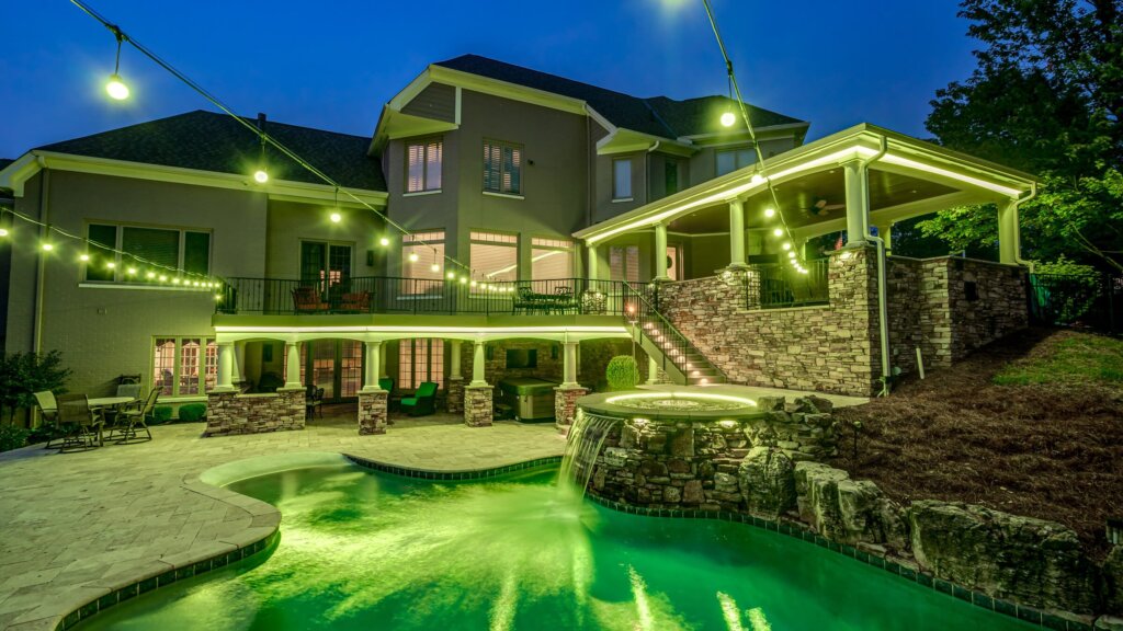 Backyard pool, patio and trees with green pool deck permanent outdoor lighting