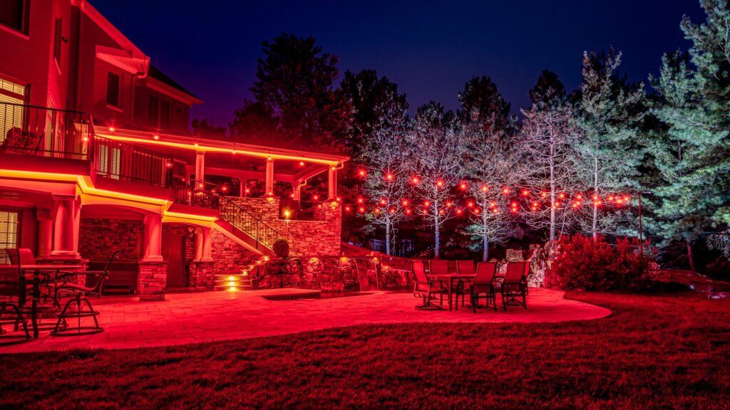 Backyard pool, patio and trees with red permanent outdoor lighting