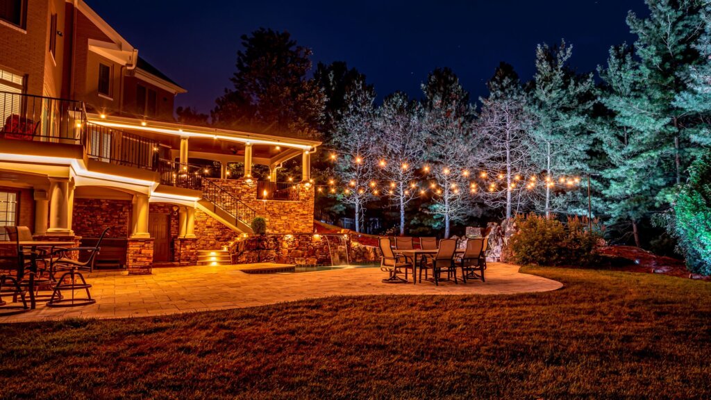 Backyard pool, patio and trees with warm white string lights permanent outdoor lighting
