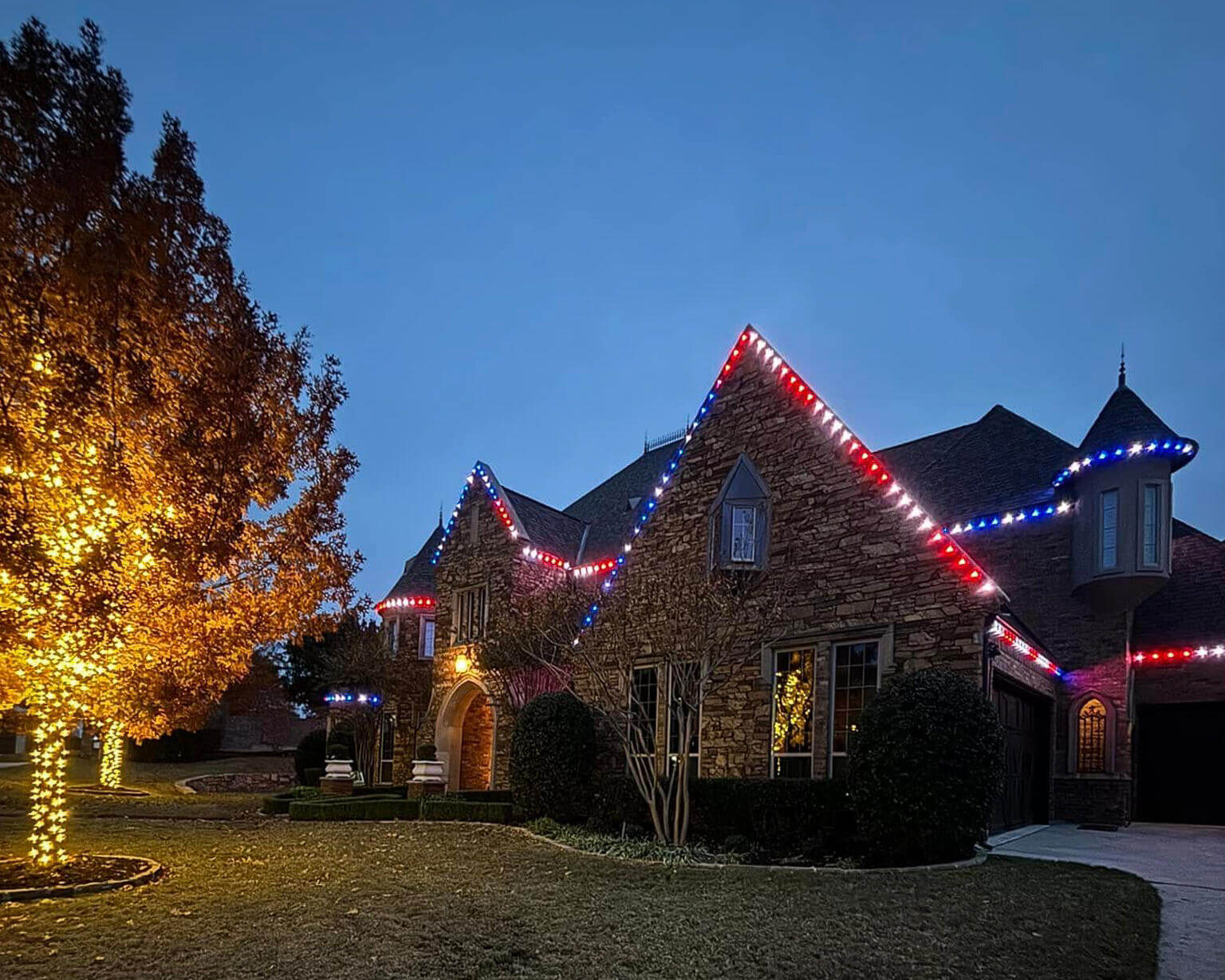 Stone home with red, white and blue permanent roofline lights